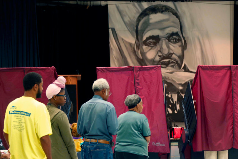 Voters in line under a large drawing of  Martin Luther King, Jr.