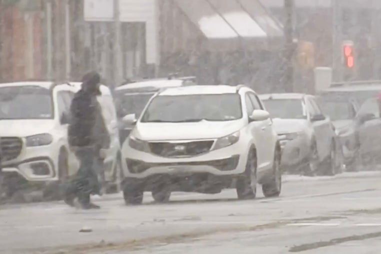 A person walks across a street amidst a snow storm.