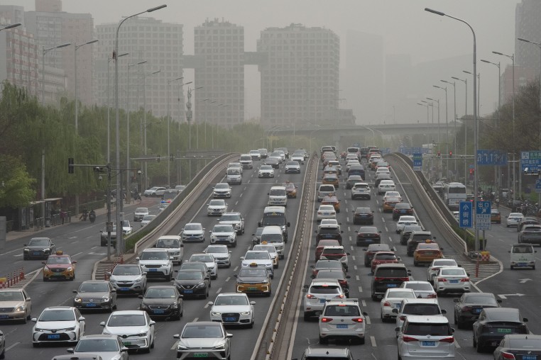Vehicles travel on a road shrouded in smog during a sandstorm warning in Beijing on April 13, 2023. 