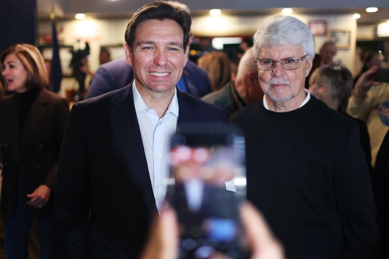 Ron DeSantis smiles for a photo  at a campaign event at a restaurant.