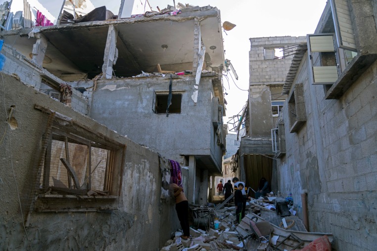 Image: Palestinians inspect a damaged building following Israeli airstrikes
