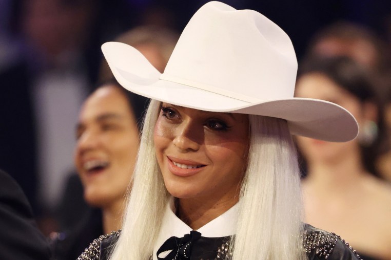 Beyoncé, wearing a cowboy hat, smiles at the Grammy Awards