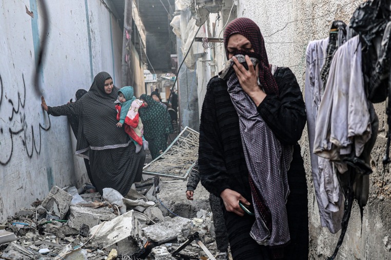 People find their way through a rubble-covered alley, following overnight Israeli bombardment in Rafah, Gaza, on Feb. 25, 2024.