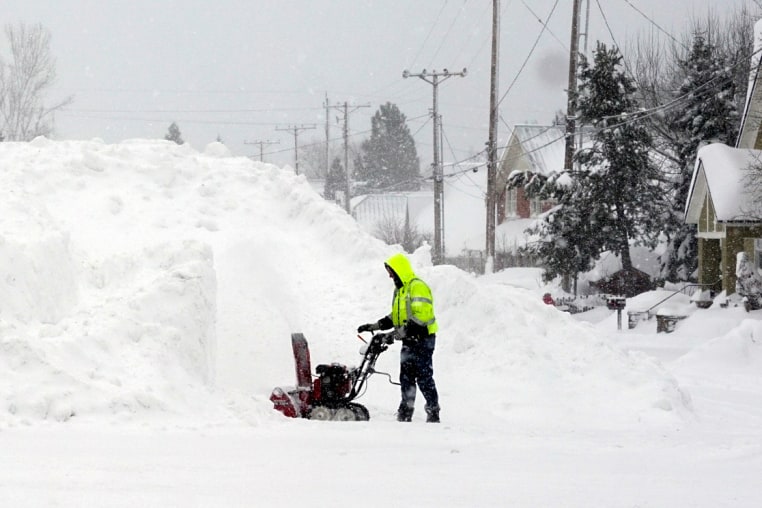 A man uses a snow blower as snow piles up during a storm in California