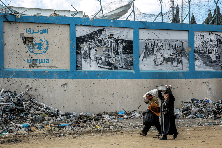 People walk past the damaged Gaza City headquarters of the United Nations Relief and Works Agency on Feb. 15, 2024.