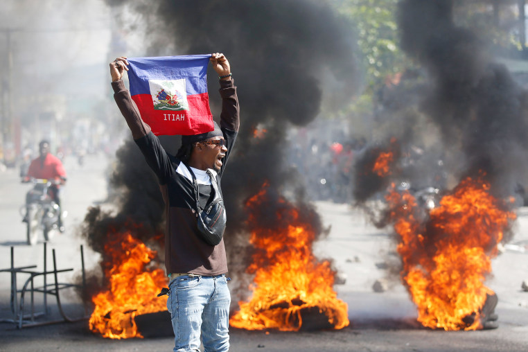 A demonstrator holds up an Haitian flag.