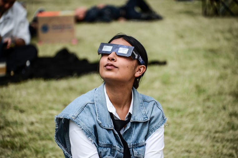 A woman watches the Annular Solar Eclipse with special sun filter glasses