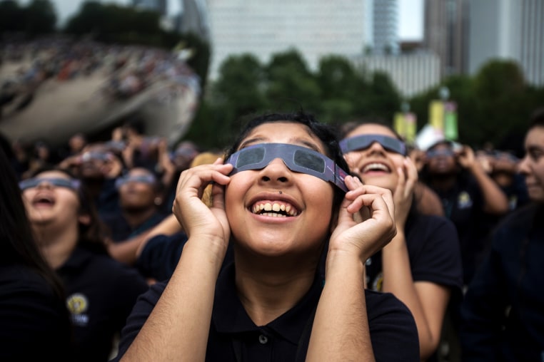 Students smile as they watch the eclipse with their glasses on.