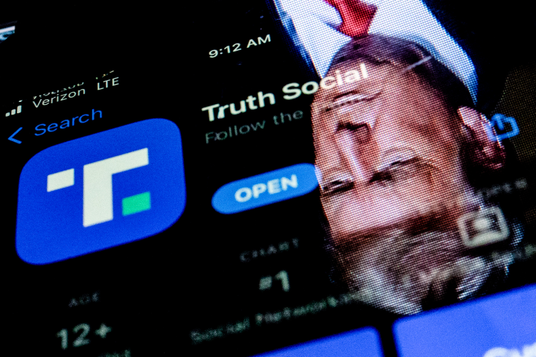 This photo illustration shows an image of former President Donald Trump reflected on a phone screen that is displaying the Truth Social app