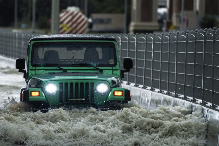 An SUV passes through standing flood water in Dubai