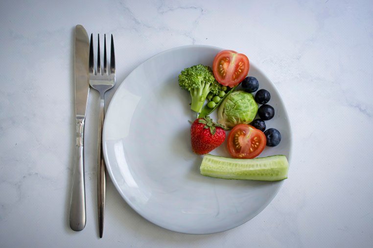 Vegetables and fruits on a plate on a light background.