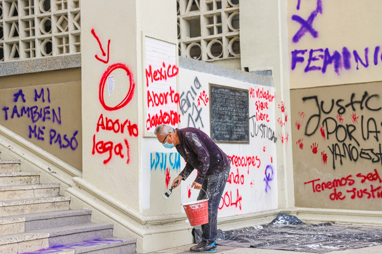A worker paints over a graffiti that reads "legal abortion" following demonstrations