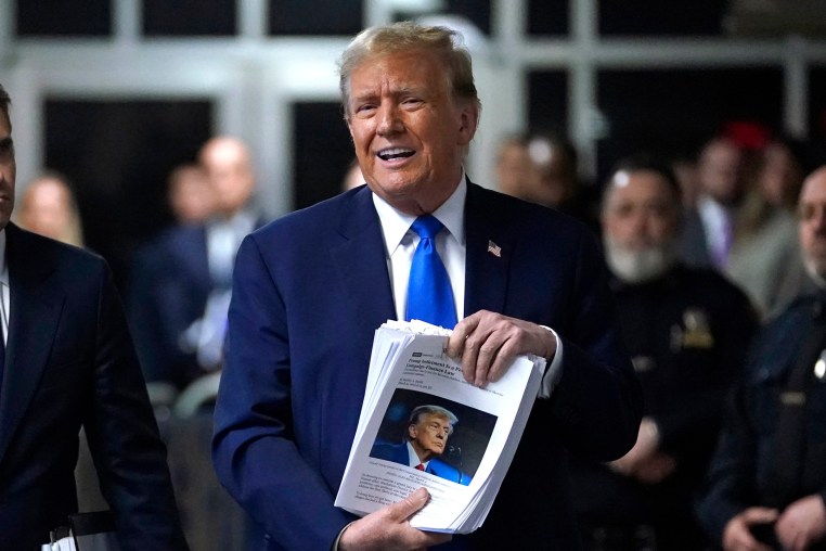 Former President Donald Trump holds news clippings as he leaves court for the day on April 18, 2024.