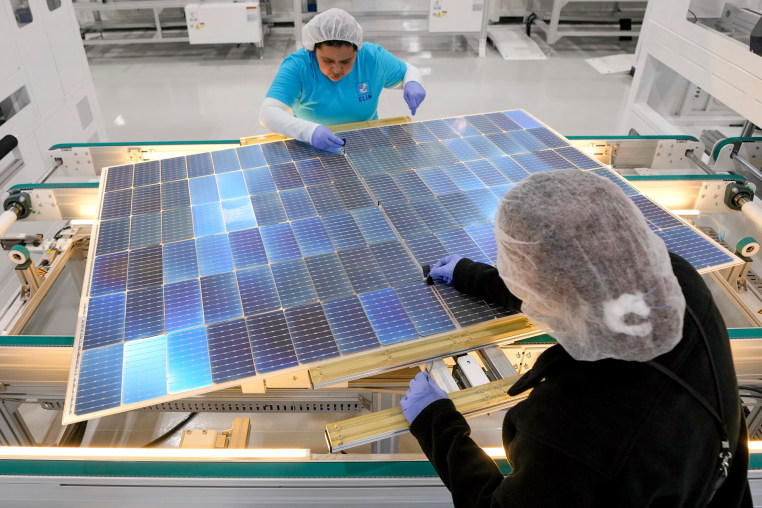 Workers assemble solar panels.