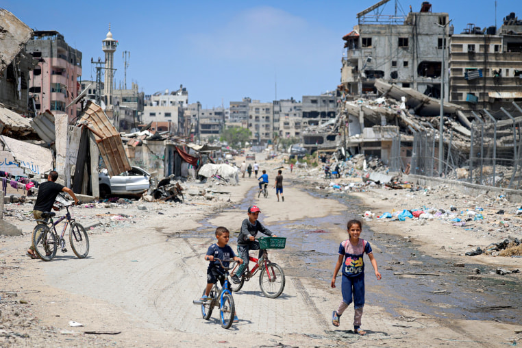Palestinian children ride their bicycles along a street devastated by Israeli bombardment.