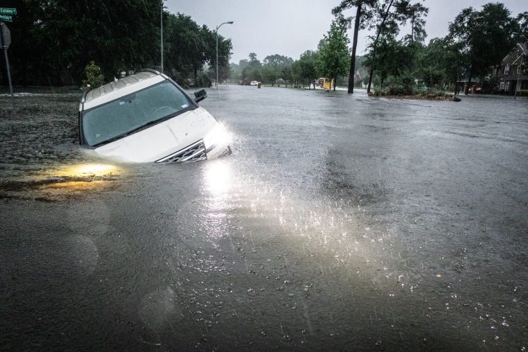 An empty car is caught in high flood waters in the rain