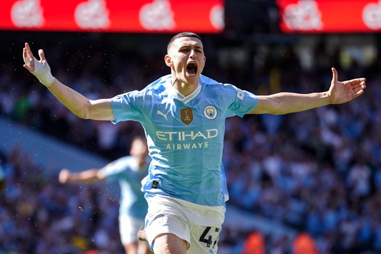 Phil Foden celebrates with arms outstretched running across the field