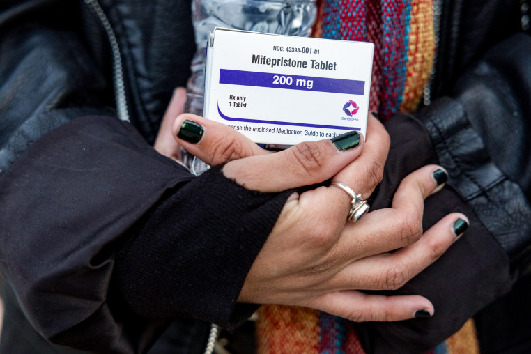 Close up of hands holding a box of mifepristone pills