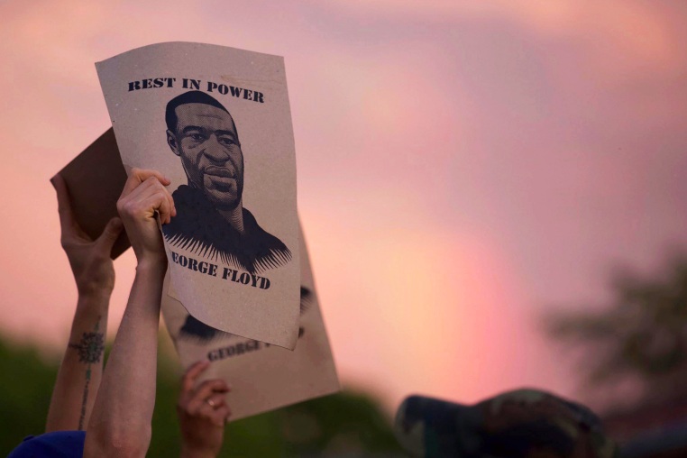 A protester holds a sign with an image of George Floyd