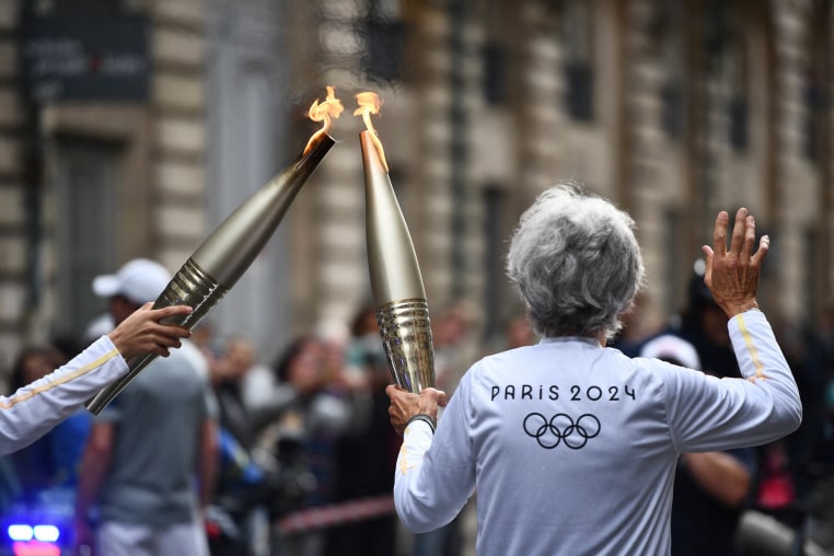 Two torch bearers carry the Olympic flame in Bordeaux, France on May 23, 2024.