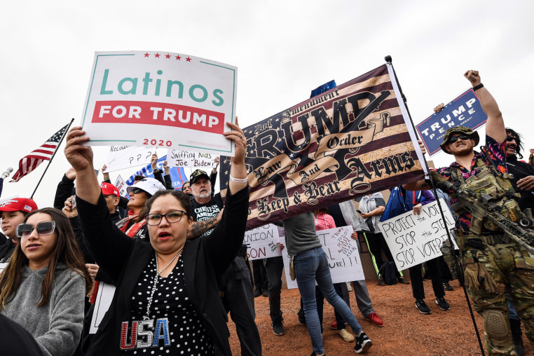 Supporters of Donald Trump hold signs, one saying "Latinos for Trump 2020"