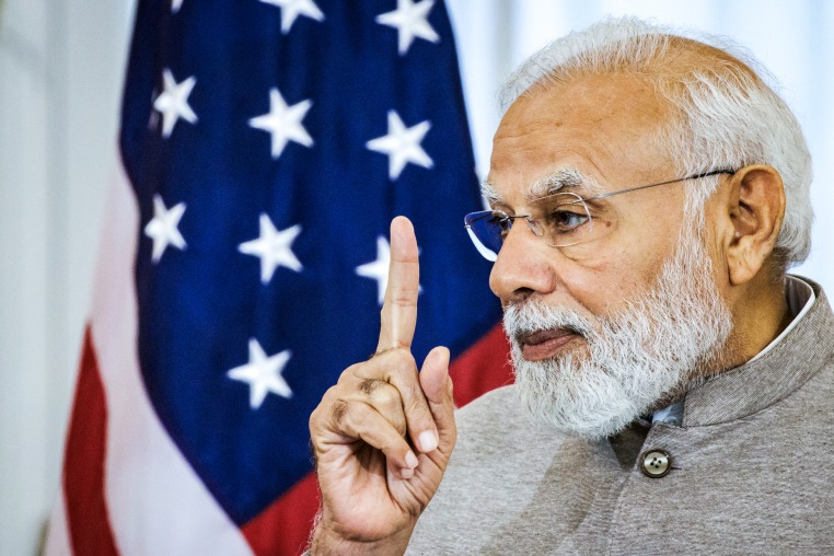 Close up of Narendra Modi point a finger up in front of an American flag