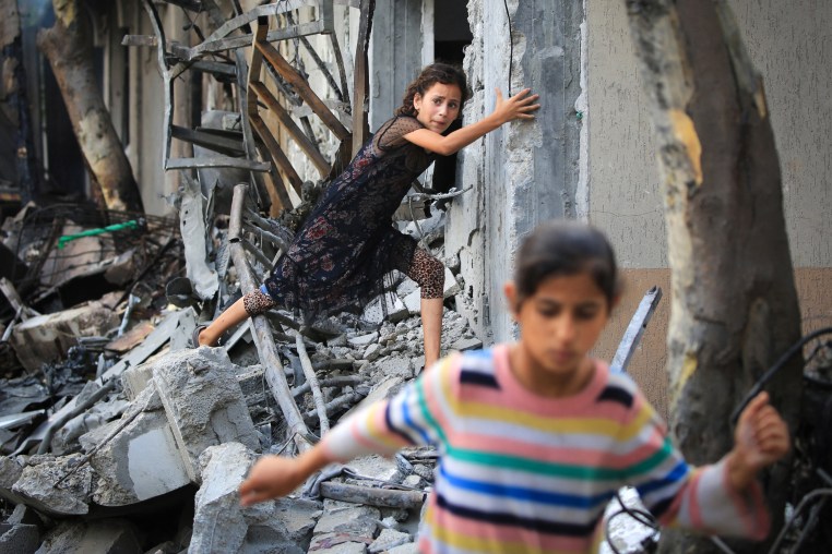 A Palestinian girl climbs over debris.