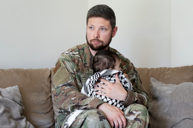 Larry Hebert, an active duty U.S. service member, hugs his daughter wrapped with a Keffiyeh in his home in Rota, southern Spain on June 20, 2024.
