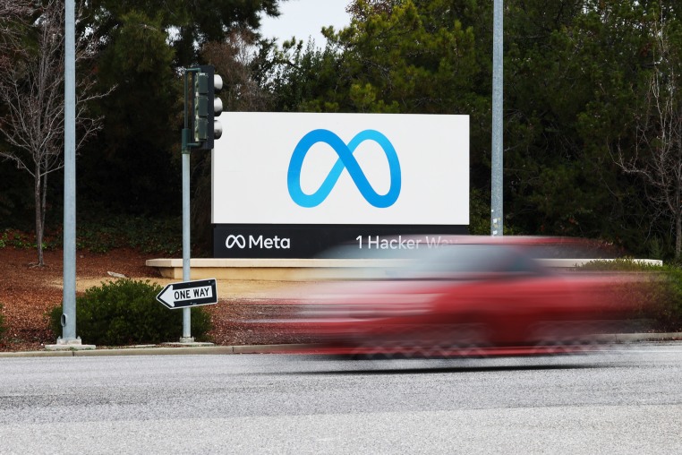 A red car drives by the Meta sign at the company's headquarters in Menlo Park