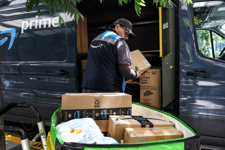 An Amazon delivery driver removes packages from a truck outside