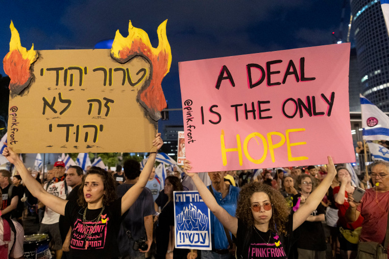 Protesters hold signs during a demonstration in Tel Aviv, Israel,