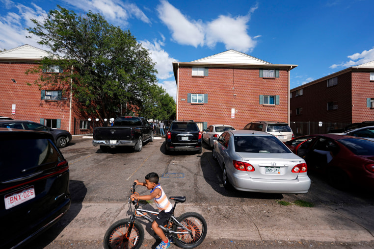 A boy guides his bicycle as a rally is held in the courtyard between apartment buildings on Sept. 3, 2024, in Aurora, Colo. Demonstrators said Venezuelans are being unfairly painted as criminals.