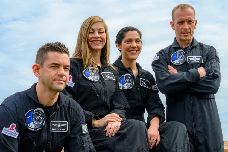 The four crew members smiling as they pose for a photo