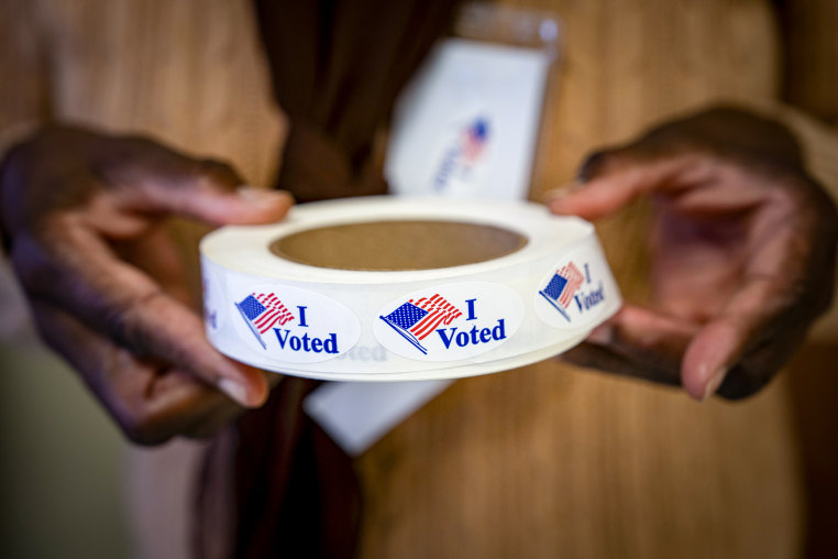 A person hols a roll of "I Voted" stickers.