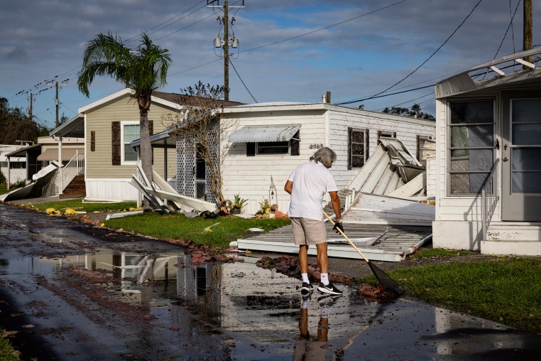 A resident cleans the front of his mobile home after Hurricane Milton's landfall