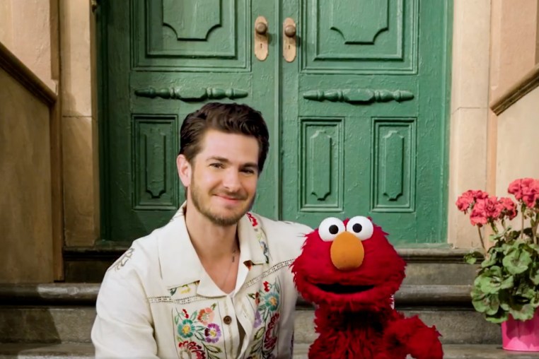 Andrew Garfield and Elmo sit on a stoop