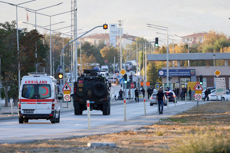 An armored personnel vehicle and an ambulance move along a road