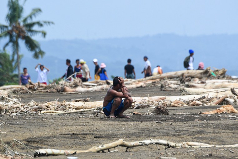 A resident sits amongst debris.