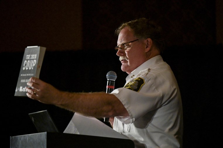 Dar Leaf, from Michigan, holds up a book titled "The 2020 Coup" 