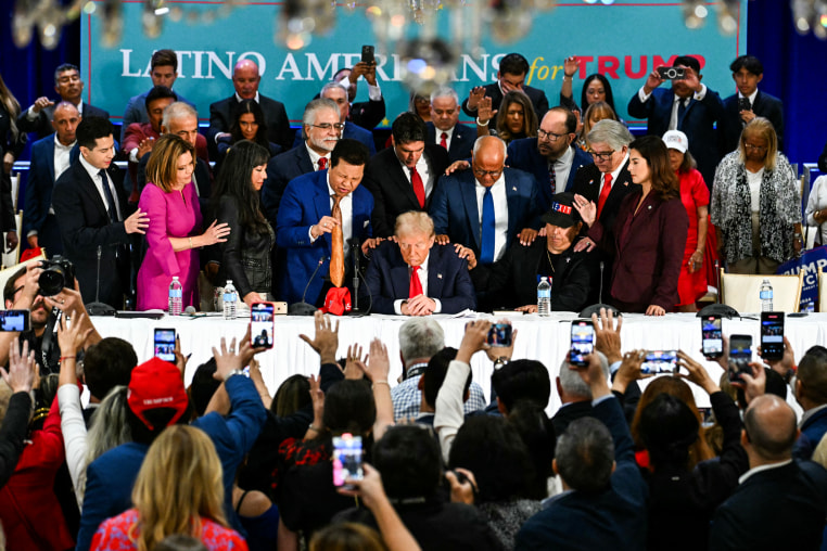 Former US President and Republican presidential candidate Donald Trump prays during a roundtable discussion with Latino community leaders in Miami, Fla. on Oct. 22, 2024.