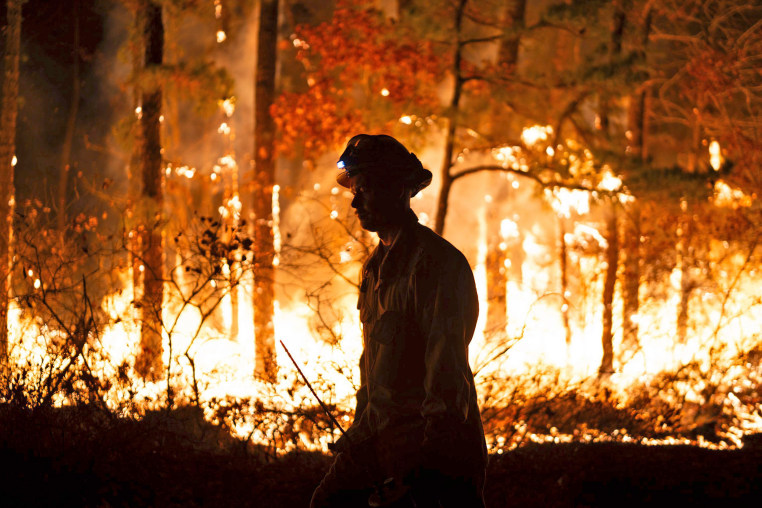 A firefighter is silhouetted against a forest fire on Wednesday, Nov. 6, 2024 in Evesham, N.J.   