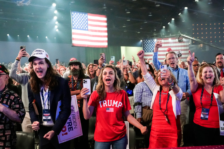 Supporters cheer in a large crows wearing Trump hats and shirts