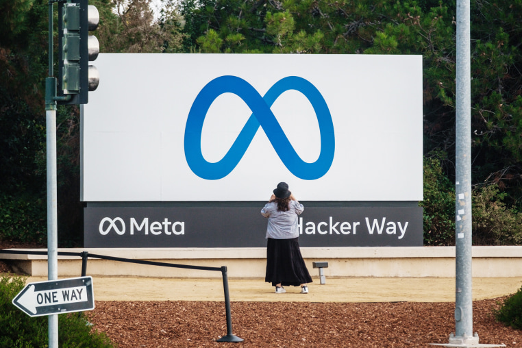 A visitor takes photographs of Meta Platforms signage outside the company's headquarters in Menlo Park