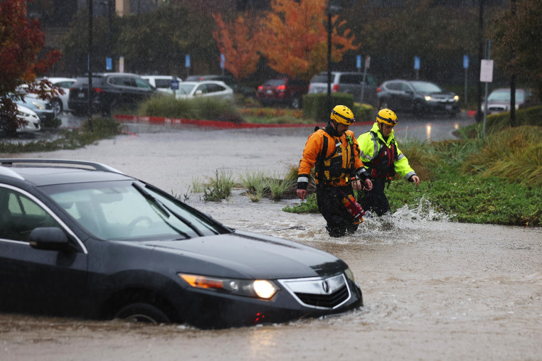 Firefighters walk through a flooded parking lot 