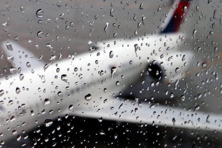 A plane sits on the tarmac behind rain drops on a window