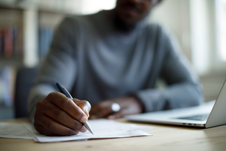 Man writing in front of laptop