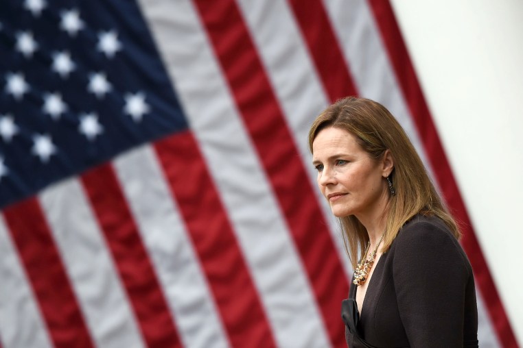 Amy Coney Barrett stands in front of an American flag