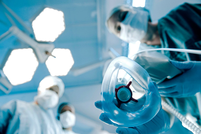Anaesthetist placing mask on patient
