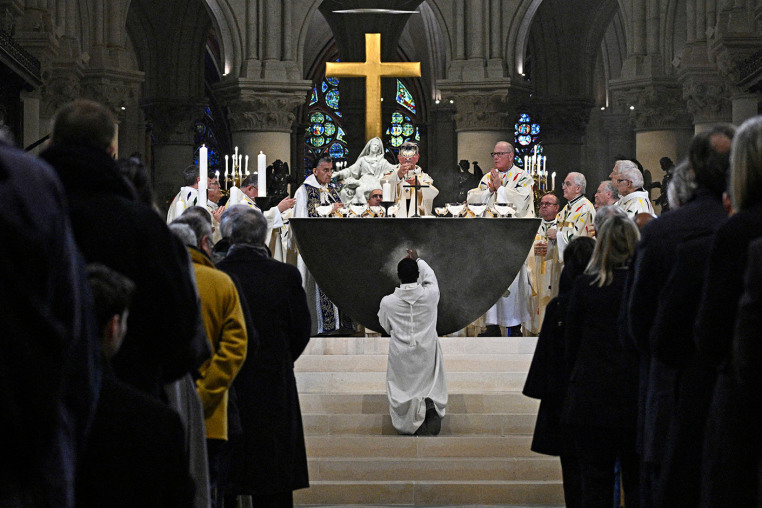 A member of the clergy kneels down as the Archbishop of Paris Laurent Ulrich leads prayers for the consecration of the new main altar at the Notre Dame cathedral 