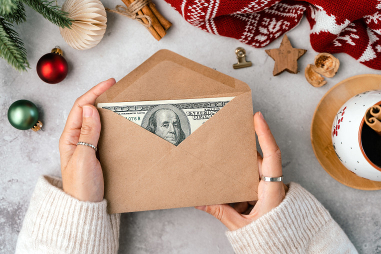 A woman holds an envelope with a  $100 bill